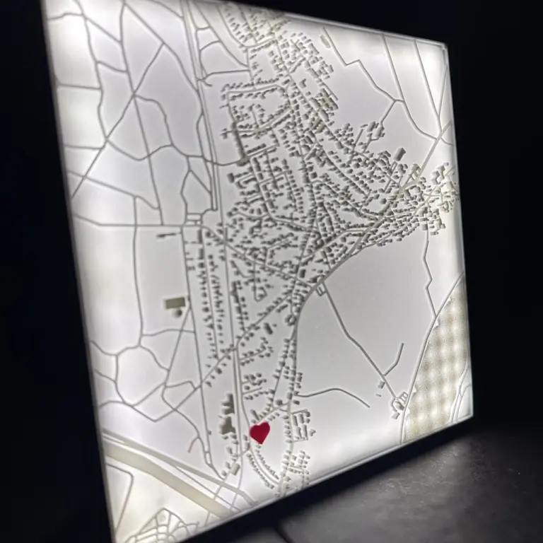 Straßenkarte in 3D rund um eine Wunschadresse. Die Adresse wird mit einem roten Herz markiert. Die Karte sitzt in einem Rahmen, der beleuchtet werden kann.